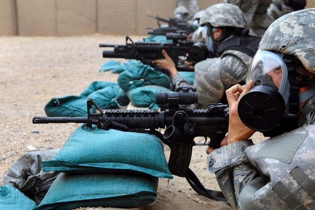 soldiers aiming weapons on sandbags